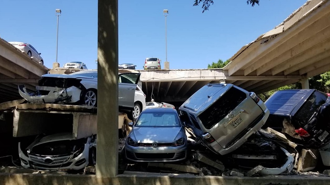 Cars sit piled on top of each other after the upper section of a parking garage in Irving, TX, collapsed on Tuesday, July 31, 2018.