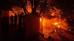 Three firefighters hose down a structure on Ridge Drive to slow the spread of the Carr Fire to other structures on July 26, 2018, in Redding, CA.