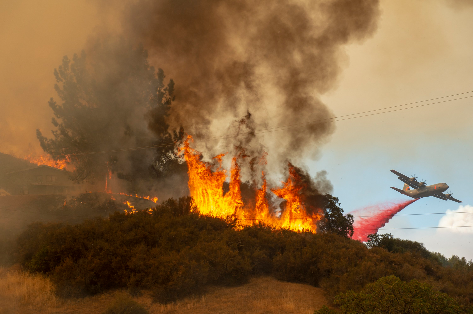 Fire retardant is dropped near a home as the Mendocino Complex Fire burns near Lakeport on July 30, 2018.