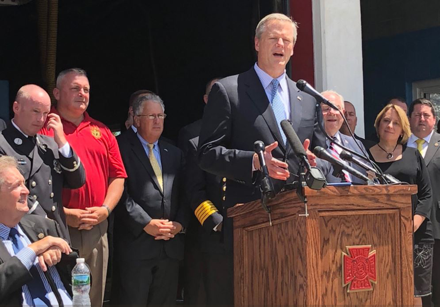 The Professional Fire Fighters of Massachusetts and Gov. Charlie Baker, pictured at lectern, worked on a bill to designate cancer as a work-related injury for state firefighters.