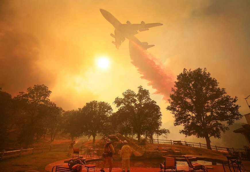 Crew members look on as a firefighting plane drops flame retardant material on the Mendocino Complex Fire on Friday, Aug. 17, 2018.