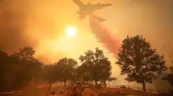 Crew members look on as a firefighting plane drops flame retardant material on the Mendocino Complex Fire on Friday, Aug. 17, 2018.