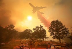 Crew members look on as a firefighting plane drops flame retardant material on the Mendocino Complex Fire on Friday, Aug. 17, 2018.