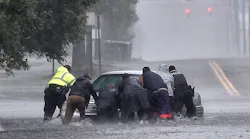 As rain from Hurricane Florence falls, police officers help civilians push a stranded motorist out of flood waters in Lumberton, NC, on Saturday, Sept. 15, 2018.