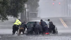 As rain from Hurricane Florence falls, police officers help civilians push a stranded motorist out of flood waters in Lumberton, NC, on Saturday, Sept. 15, 2018.