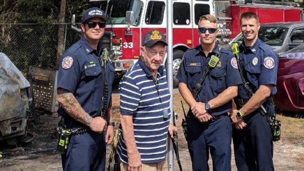 Marion County firefighters pose with an unidentified Air Force veteran whose American flag was burned during a vehicle fire at his home in Ocala, FL, on Monday, Oct. 1, 2018.