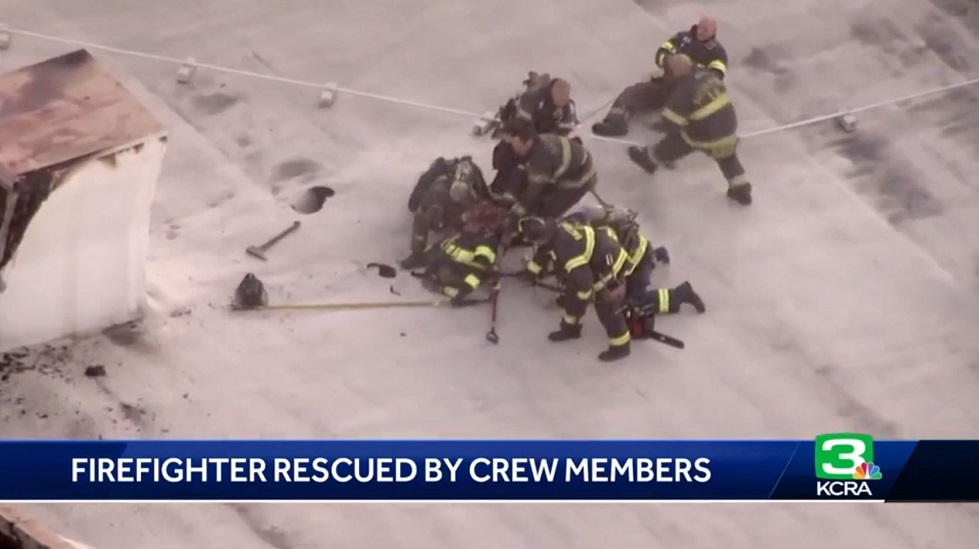 Sacramento firefighters pull a colleague to safety after he began to fall through the roof of a commercial building during a fire on Wednesday, Oct. 24, 2018.