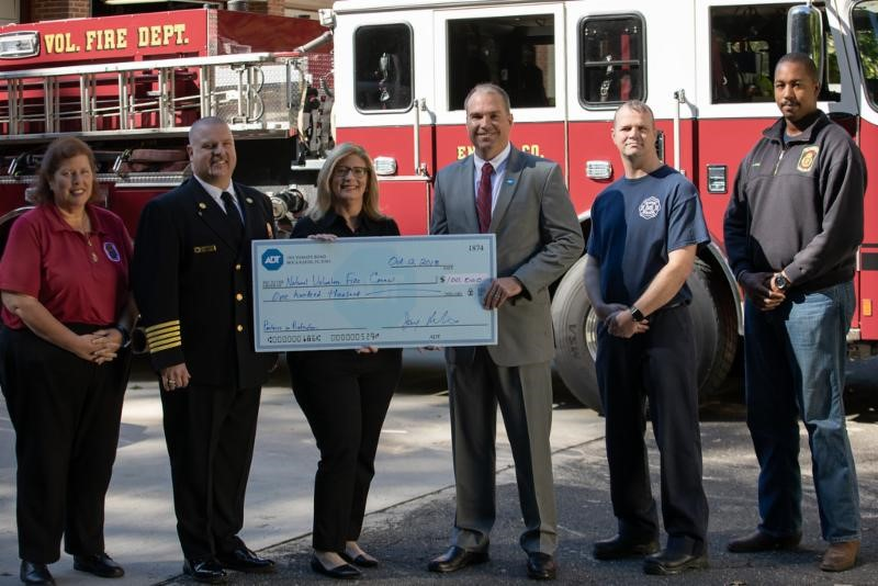 ADT&rsquo;s Jay Robertson (center), who is also a volunteer firefighter, presents a $100,000 contribution to Heather Schafer, CEO of the NVFC.