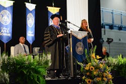 Columbia Southern University President Ken Styron speaks at the 2018 commencement on Oct. 19 as keynote speaker J.R. Martinez looks on seated behind him.