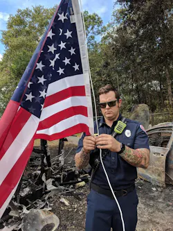 A Marion County firefighter hangs an American flag after another was damaged by a vehicle fire at the home of an Air Force veteran in Ocala, FL, on Monday, Oct. 1, 2018.