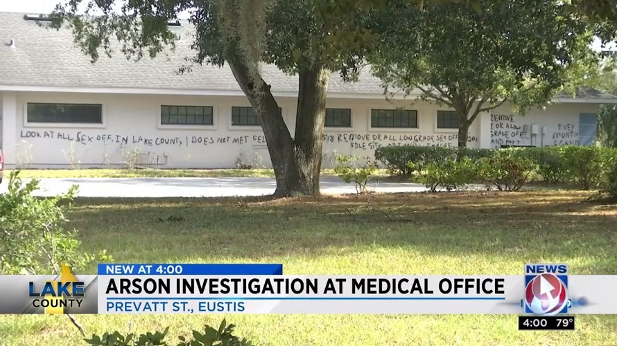 A cryptic graffiti message is scrawled across a building in Eustis, FL, that may be the work of the same person who set 10 cars on fire in an adjacent parking lot on Sunday, Nov. 18, 2018.