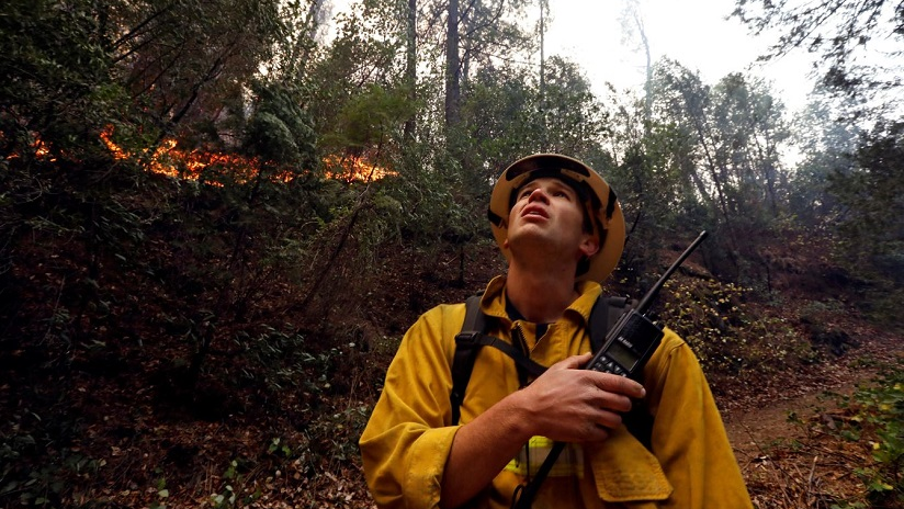 Firefighter Brian Carter of Weed, CA, keeps an eye on Camp Fire flames burning along the North Fork of the Feather River in Butte County on Sunday, Nov. 11, 2018.