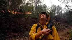Firefighter Brian Carter of Weed, CA, keeps an eye on Camp Fire flames burning along the North Fork of the Feather River in Butte County on Sunday, Nov. 11, 2018.