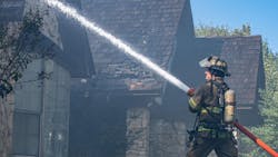 A Fort Worth firefighter pours water on a residential fire on Oct. 11, 2018.