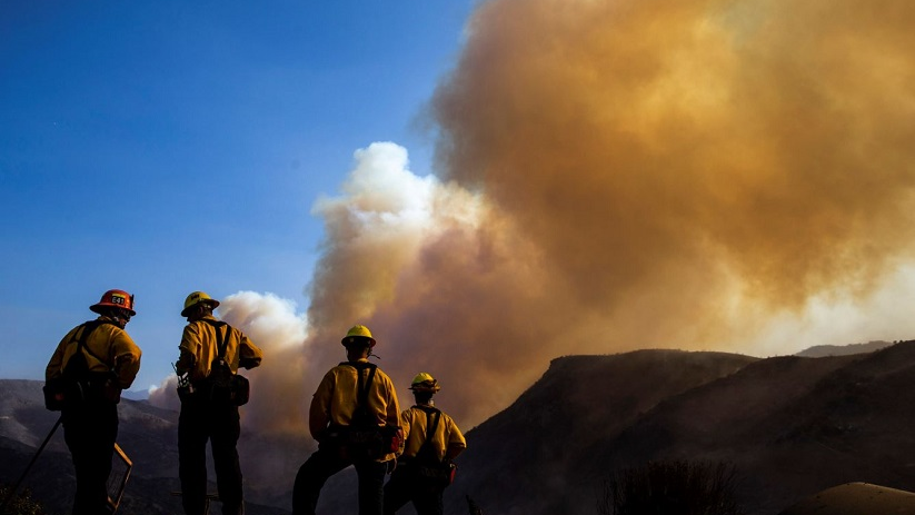 Firefighters watch as a plume of smoke rises from the Woolsey Fire near the Chatsworth reservoir on Sunday, Nov. 11, 2018, in Los Angeles, CA.