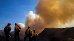 Firefighters watch as a plume of smoke rises from the Woolsey Fire near the Chatsworth reservoir on Sunday, Nov. 11, 2018, in Los Angeles, CA.