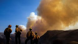 Firefighters watch as a plume of smoke rises from the Woolsey Fire near the Chatsworth reservoir on Sunday, Nov. 11, 2018, in Los Angeles, CA.