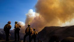 Firefighters watch a plume of smoke rise from the Woolsey fire near the Chatsworth reservoir on Nov. 11, 2018, in Los Angeles.