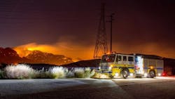 Ventura County, CA, Fire Department Engine 43 stands watch in Woolsey Canyon during the early stages of the Woolsey Fire. The streak of light at center-left in the background is a helicopter making a water drop.