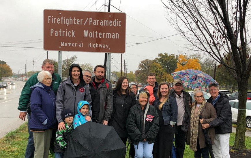 The family of fallen Hamilton, OH, firefighter Patrick Wolterman poses in front of a sign dedicating a stretch of Route 4 in his honor on Thursday, Nov. 1, 2018.