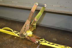 After tightening a ratchet tie-down unit as fully as necessary by hand, rescuers should close the handle, so it latches over the sprocket slide bar and secures the mandrel core in position.