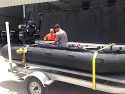 Crewmembers install a surface-drive mud motor on a military-style rescue boat.