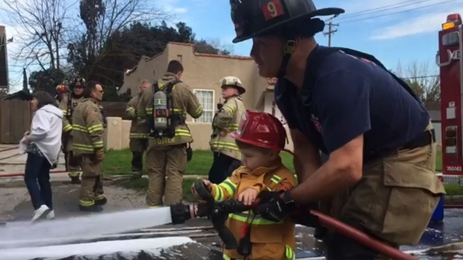 A Fresno, CA, firefighter helps 2-year-old Jackson McNary handle the hose during a recent call.