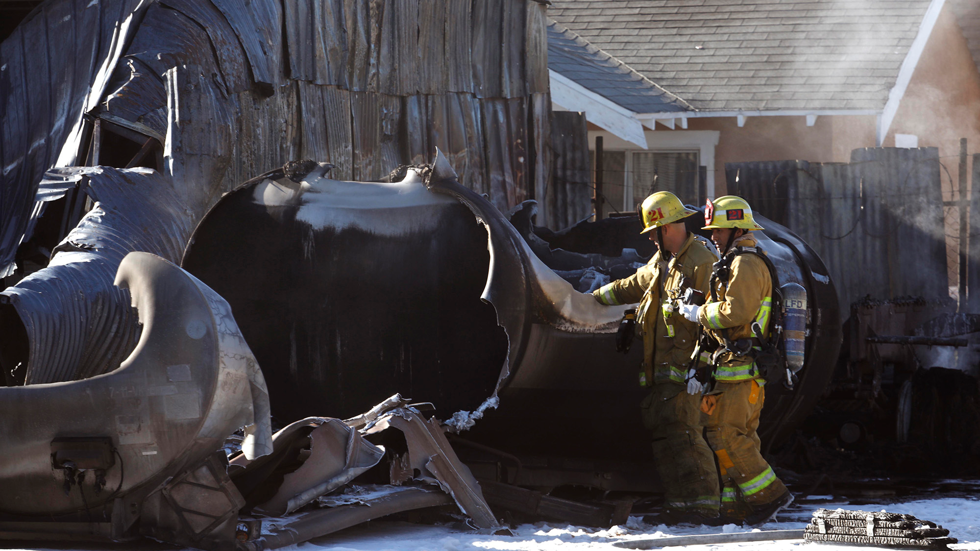 Firefighters look over a tank that exploded, causing a fire and manhole covers to shoot into the sky Sunday morning in Los Angeles.