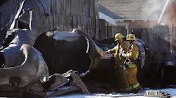 Firefighters look over a tank that exploded, causing a fire and manhole covers to shoot into the sky Sunday morning in Los Angeles.