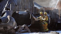 Firefighters look over a tank that exploded, causing a fire and manhole covers to shoot into the sky Sunday morning in Los Angeles.