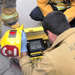Firefighters check an atmospheric monitoring device during a hazmat incident.