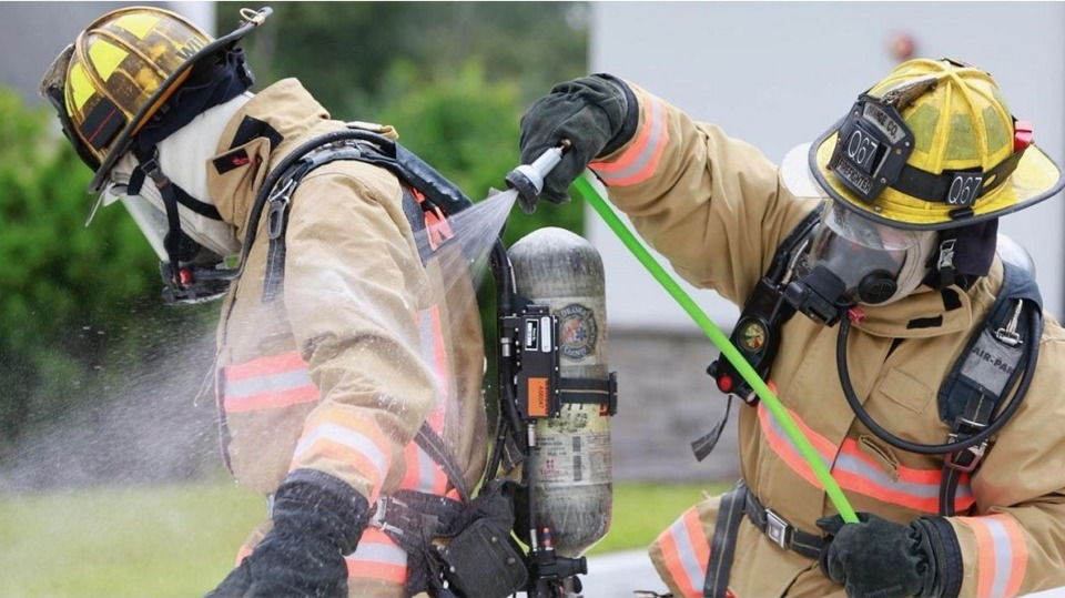 Orange County firefighters demonstrate the use of a decontamination kit to hose deadly carcinogens off their gear.