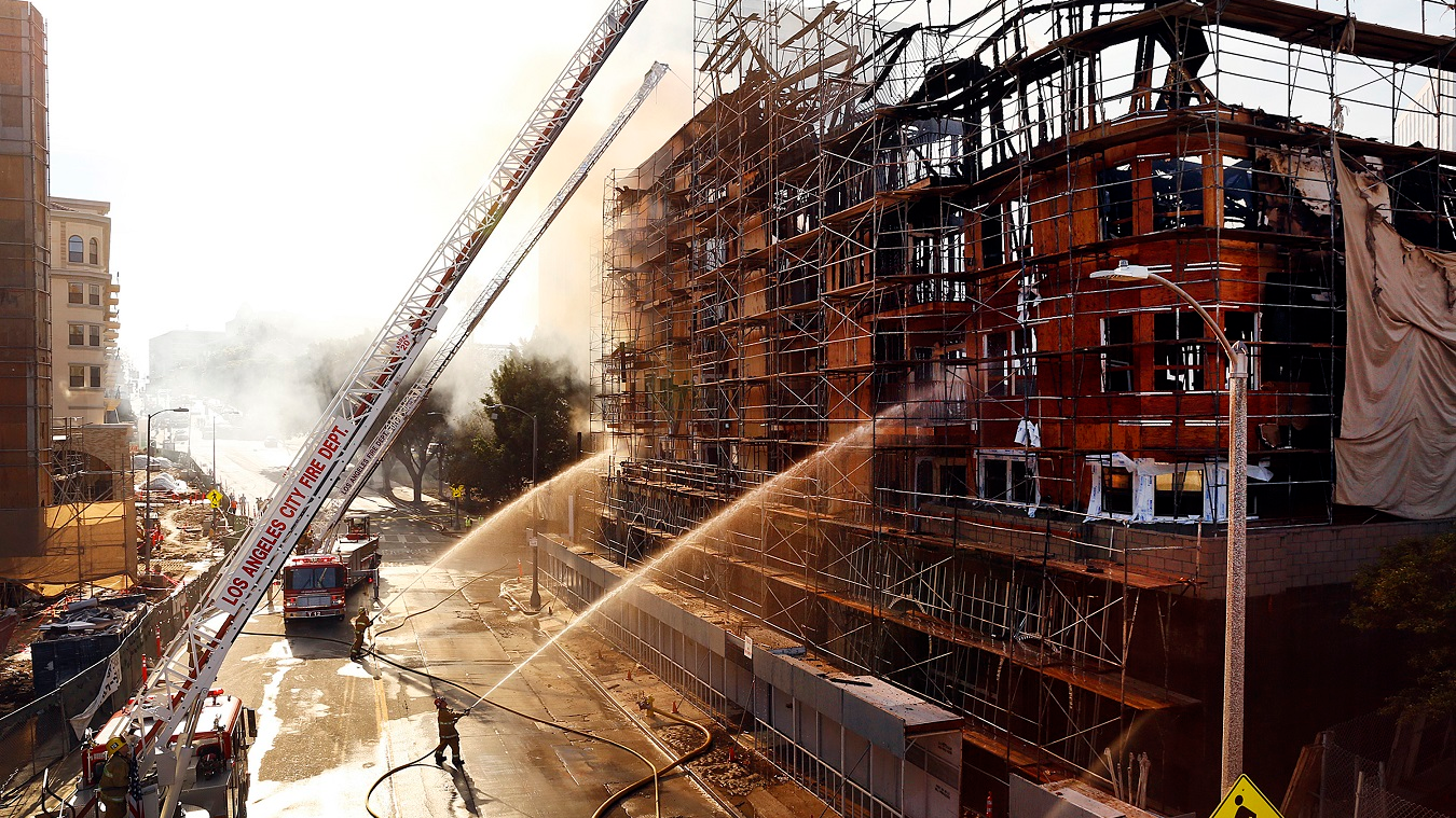 Los Angeles firefighters pour water on hot spots after a massive fire at an apartment complex construction site on Dec. 8, 2014.