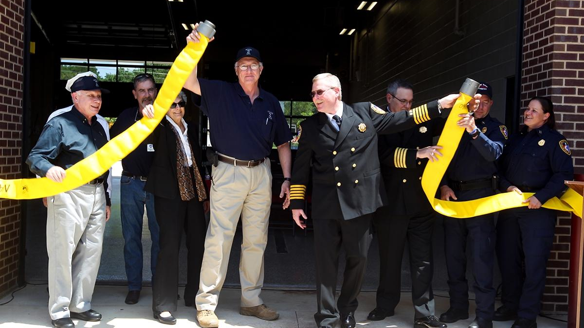ESD No. 2 President Thomas Nanninga (left) and Sam Bass Fire Chief David Kieschnick, center, perform a fire hose uncoupling during the grand opening of the ESD No. 2 and Sam Bass Fire Department Fire Station No. 3.