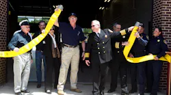 ESD No. 2 President Thomas Nanninga (left) and Sam Bass Fire Chief David Kieschnick, center, perform a fire hose uncoupling during the grand opening of the ESD No. 2 and Sam Bass Fire Department Fire Station No. 3.