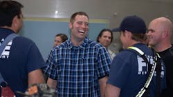 Anchorage, AK, firefighter Ben Schultz laughs with colleagues at a welcome home party after he spent time at a trauma center in Omaha, NE, recovering from a fall that nearly killed him.