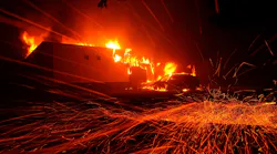 Embers blow in the wind as the Camp Fire burns a KFC restaurant in 2018 in Paradise, CA.