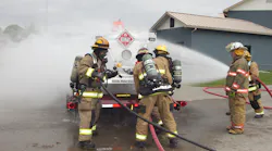 Hazmat personnel provide water spray to disperse vapors while hooking up water injection equipment.