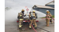 Hazmat personnel provide water spray to disperse vapors while hooking up water injection equipment.