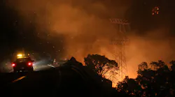 A firefighter peers over a cliff at the Camp fire burning on Highway 70 west of Pulga, CA., in Butte County in 2018.