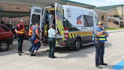 During the active shooter training, EMTs and firefighters from Lafourche and Terrebonne parishes in Louisiana assist an injured man into an ambulance while an officer stands guard at the scene.