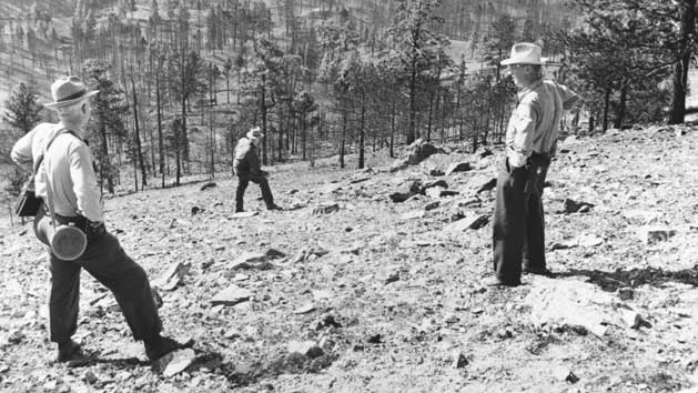Investigators stand on the steep, barren north slope of Montana's Mann Gulch, where a wildfire killed 12 smokejumpers on Aug. 5, 1949.