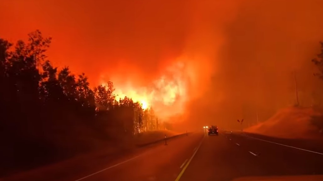 Drivers navigate through heavy smoke and flames caused by the Swan Lake wildfire near Sterling, AK.