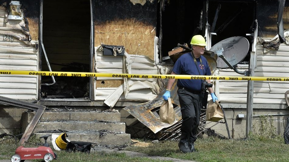 Erie Police Detective Lt. Chris Crawford carries possible evidence from a home at 1248 West 11th St. where five children died in an early morning fire on Sunday, Aug. 11, 2019.