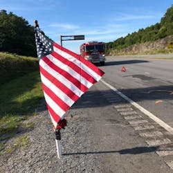 A flag and memorial was erected near the site of the two-vehicle accident in Powell Mountain, WV, that killed two Jan-Care Ambulance Service EMTs on Saturday.