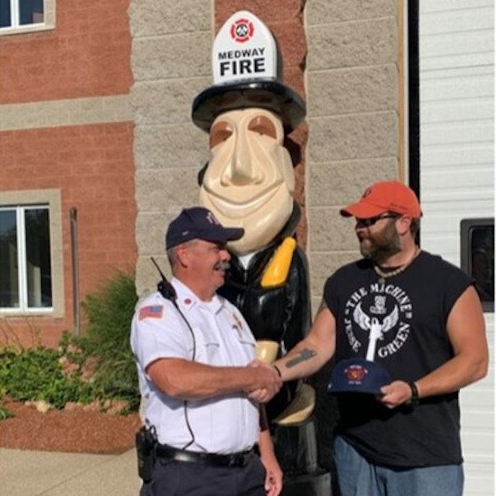 Medway, MA, Fire Chief Jeffrey Lynch (left) and chainsaw sculptor 'The Machine' Jesse Green, who created and refurbished the wooden sculpture that sits outside the department's fire station.