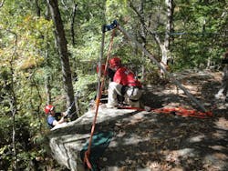 Firefighter participating in Advanced Wilderness Rope Rescue Course is lowered using a sideways A-frame artificial high directional.