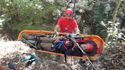 Firefighter participating in Advanced Wilderness Rope Rescue Course attends patient on a lower.
