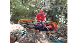 Firefighter participating in Advanced Wilderness Rope Rescue Course attends patient on a lower.