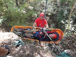 Firefighter participating in Advanced Wilderness Rope Rescue Course attends patient on a lower.